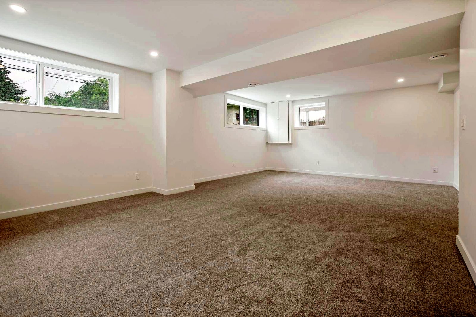 Finished basement renovation with recessed lighting and large egress windows in a Sherwood Park area home